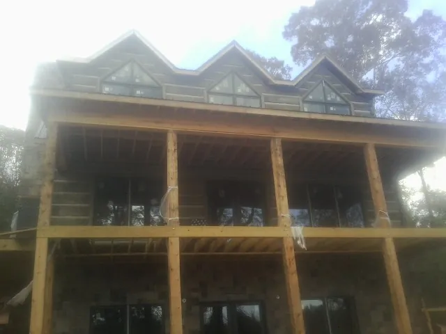 Dormers and porch framing on a large log home under construction — Roof Coating work by our crew in Bishop Hill