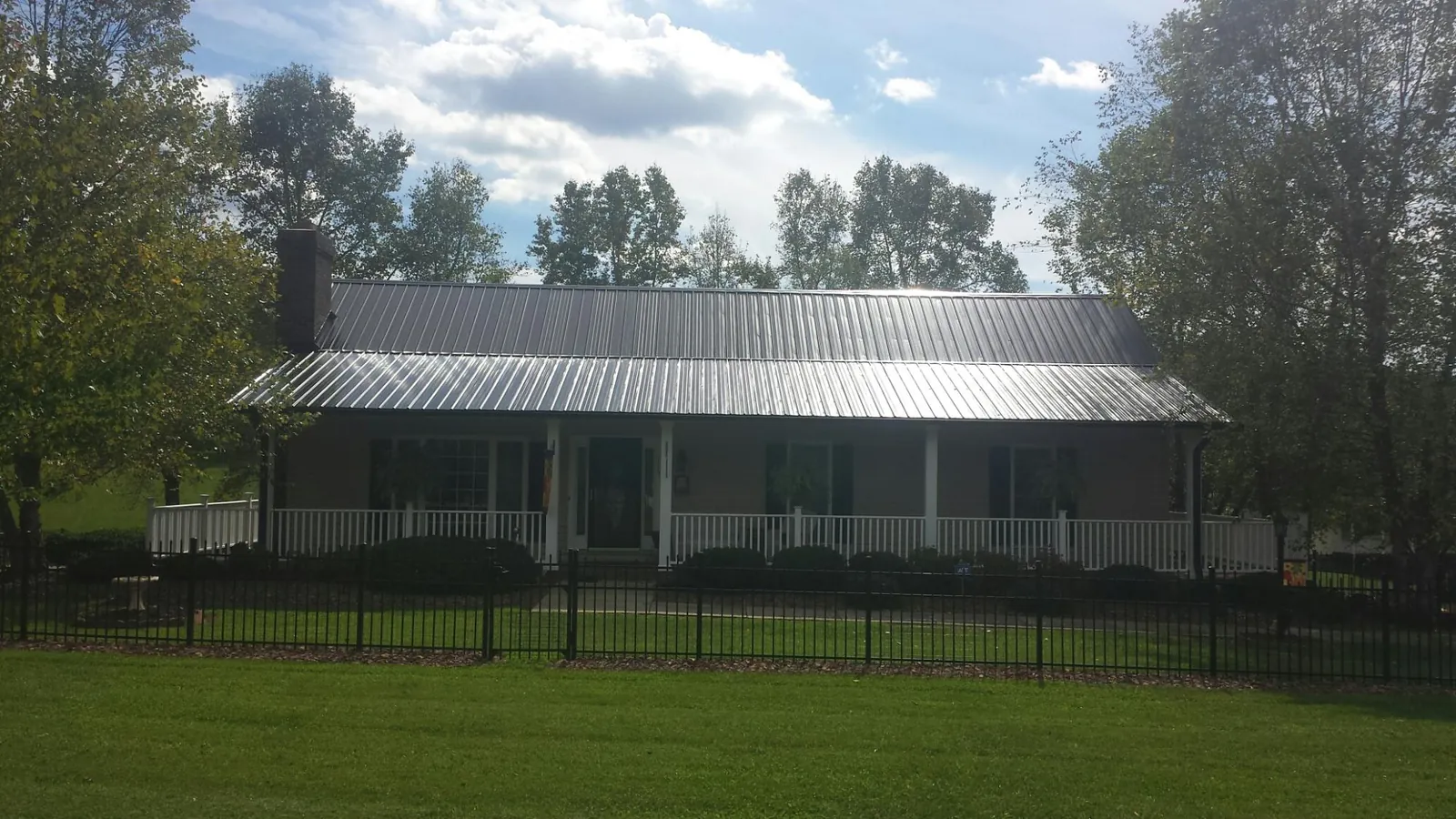 Gray metal roof on a brick ranch with a full width front porch — Gutter Guard Installation work by our crew in Bishop Hill