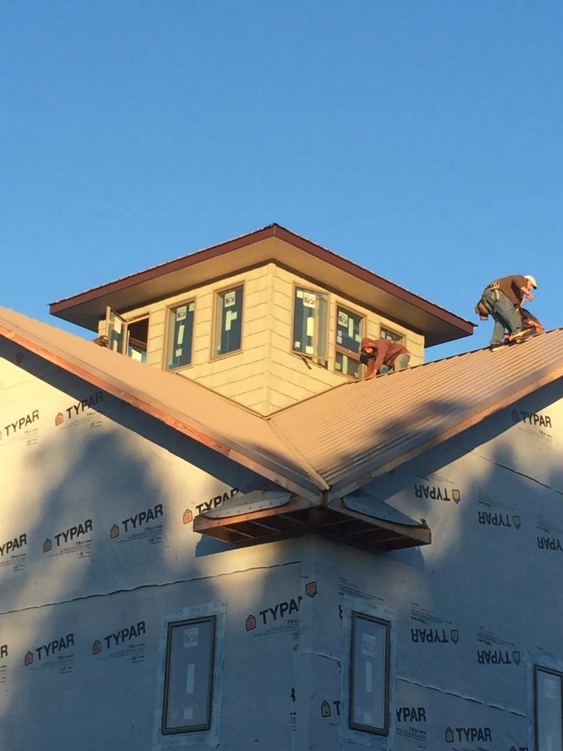 Roofers working around a rooftop cupola on a new metal roof at sunset — Roof Waterproofing in Bishop Hill by Roofing Brothers